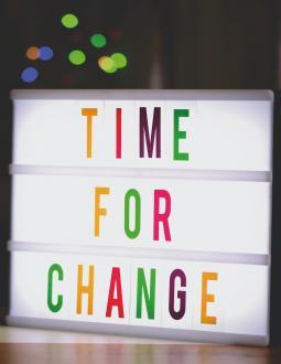Sign that reads "Time for Change". Coloured lights are in the background.
